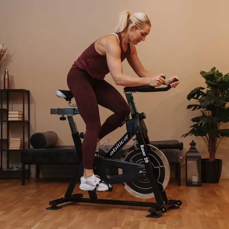 Abilica Racer 20 spinningcykel med 20 kg svinghjul, kædedrev og justerbart styr og sæde. Perfekt til hjemmetræning med ergonomisk design, flaskeholder og transporthjul for nem flytning.