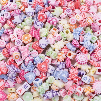 Närbild av pastellpärlor med bokstäver, bokstavskuber och former som fjärilar, hjärtan och djur