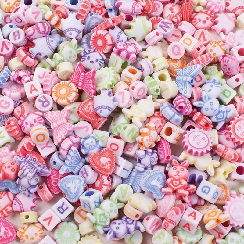 Närbild av pastellpärlor med bokstäver, bokstavskuber och former som fjärilar, hjärtan och djur