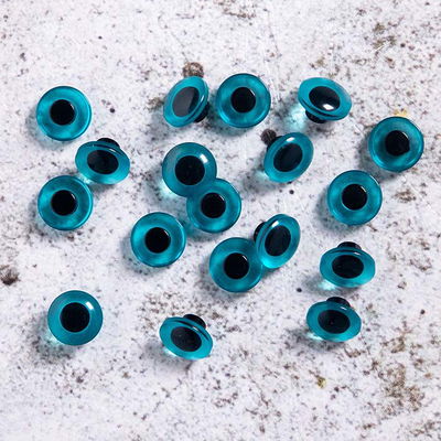 Blå knappögon 12 mm, utspridda på underlag av betong