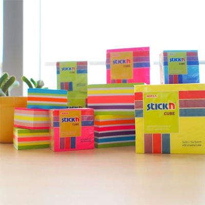 Flera olika notisblock från Stick'n på en yta med fönster bakom