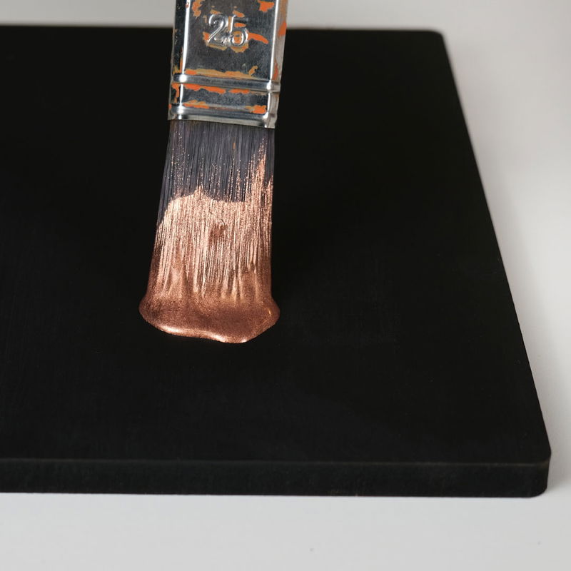 Kopparpulver imitationspulver med hobbylack på svartmålad skiva