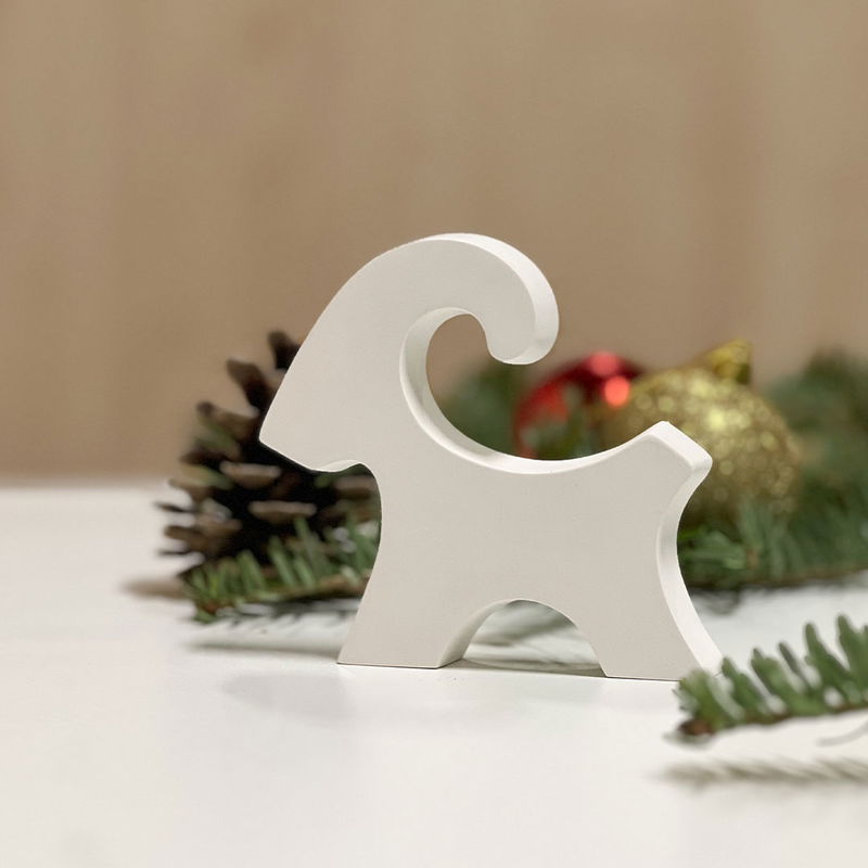 Liten julbock i formgips Liten gjuten julbock i vitt betonglikt material med juldekoration