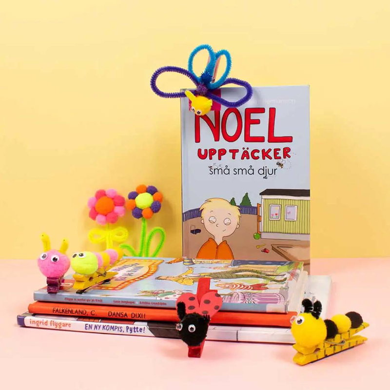 Pompomfigurer av bi, nyckelpiga och blomma med piprensare och plastögon vid barnböcker