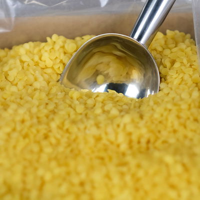 Närbild på gult bivax i pellets med metallskopa, naturligt och perfekt till bivaxdukar, ljus och mer