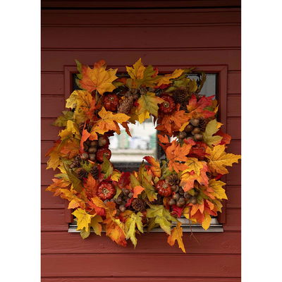 Höstkrans med ekollon och löv på röd vägg