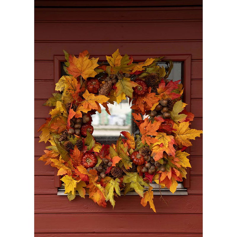 Höstkrans med ekollon och löv på röd vägg