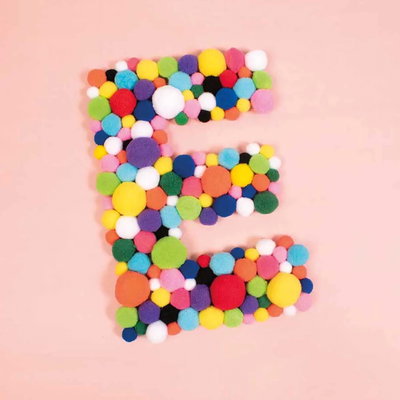 Stor bokstav E formad av pompoms i blandade basfärger mot rosa bakgrund