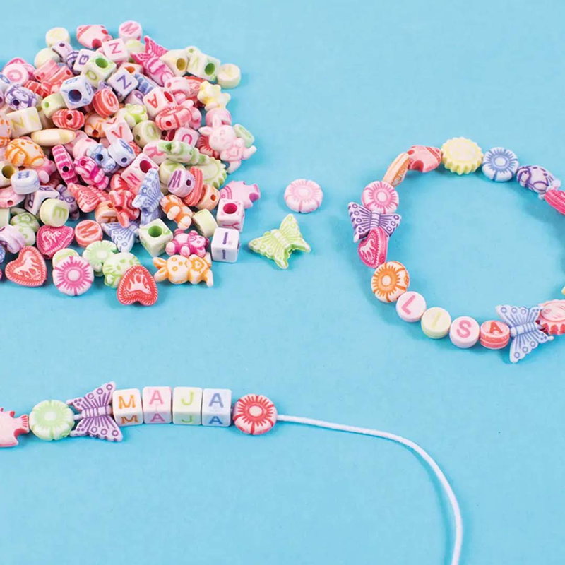 Pärlor i pastellfärger och färdiga armband med namnen LISA och MAJA av bokstavspärlor