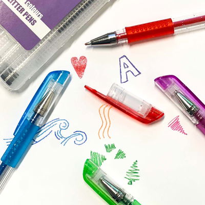 Glitterpennor i användning med små doodles och tester i färgerna röd, blå, grön och lila