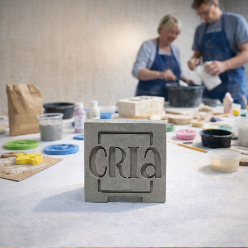 Bild som representerar Cria Gjutkurs. På bilden finns crias logga uppgiften i betong, andra gjuttillbehör och två personer i bakgrunden