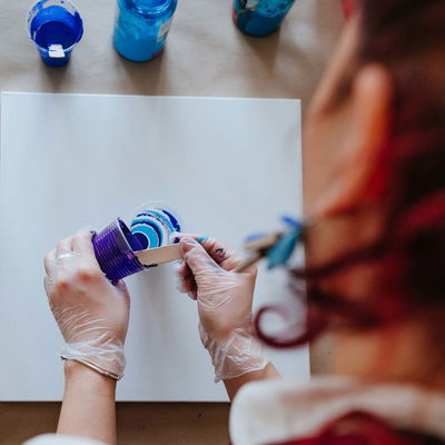 Medium som tunnar ut akrylfärg, pouring-medium, som appliceras på en canvas, färgerna går i blått och turkos