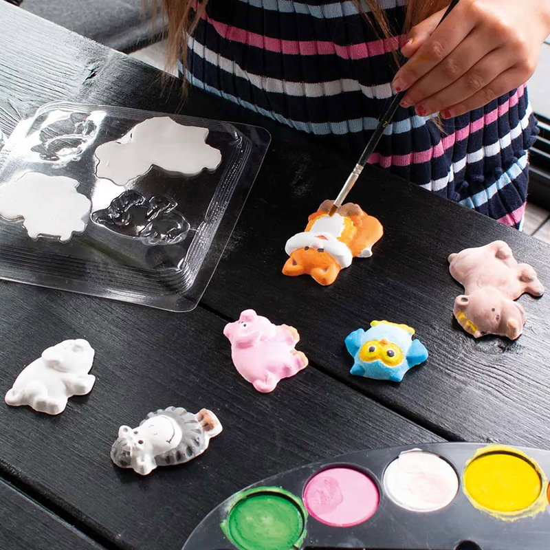 Barn målar gjutna gipsfigurer i modellgips med vattenfärg bredvid silikonform