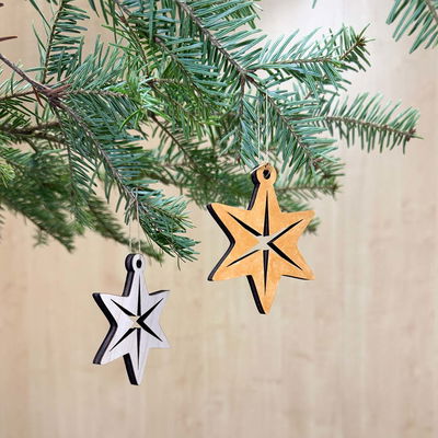 Julhänge Stjärna Nordisk, stilren trädekoration med nordisk känsla Två stjärnformade julhängen i trä, en målad i guld och en i naturlig plywood, hängande i gran