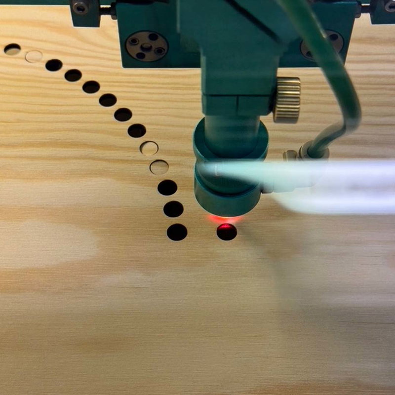 Laserskärare som skär i furuplywood, cirkelhål