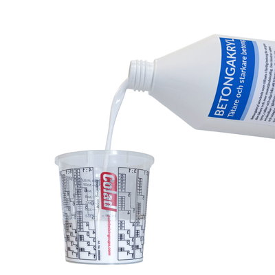 Vit Betongakryl-vätska hälls i mätbägare med graderingar för exakt dosering