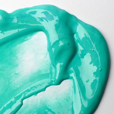 Blankt turkost färgprov blandat med Liquitex Gloss Medium på vitt papper