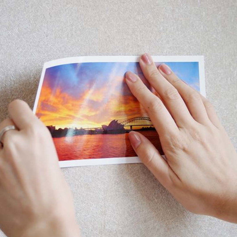 Händer fäster en poster på vägg med flyttbar dubbelhäftande tejp