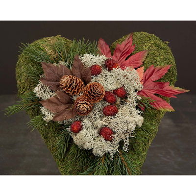 Grönt hjärta dekorerat med röda björnbär, mossa och kottar