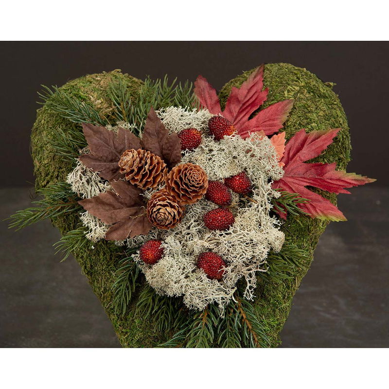 Grönt hjärta dekorerat med röda björnbär, mossa och kottar