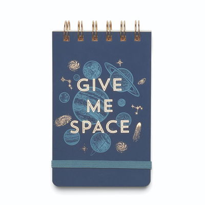 Anteckningsblock med texten Give Me Space med rymdillustration. Texten och spiralbindningen är i guldfärg