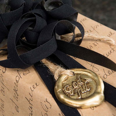 Paket inslaget med brunt papper och svart snöre dekorerat med guld-sigil