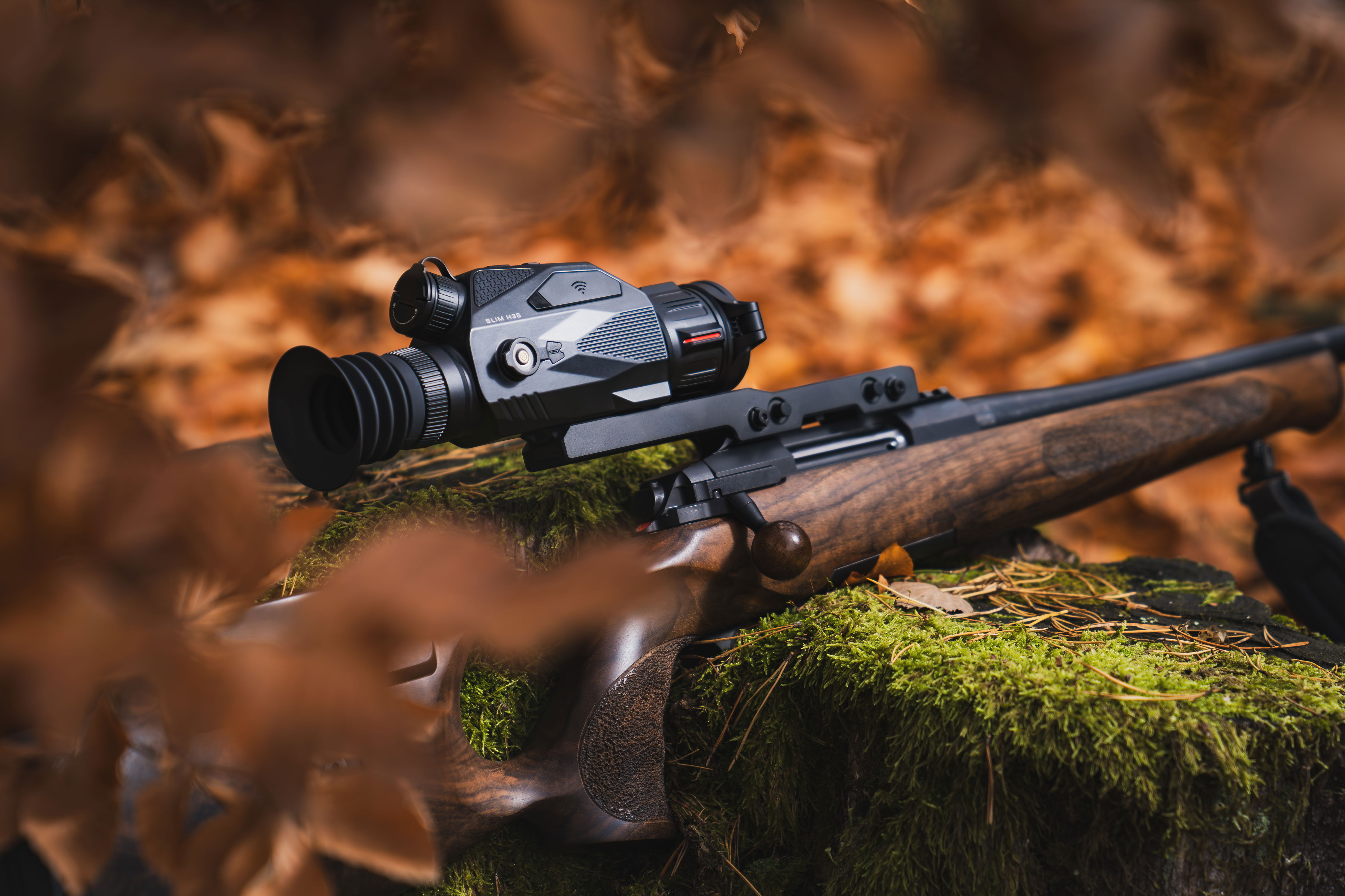 Bild på SLIM-kikarsikte från Nocpix monterat på ett vapen med skog i höstmiljö runtom