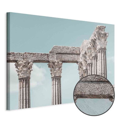 Schuin productaanzicht van Pillars of history wide. Het motief loopt door over de randen van het canvas. Een ronde detailopname toont het reliëf van het geloppervlak.