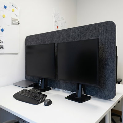Bulletin Desk Screen gray desk screen behind computer monitors in an office setting