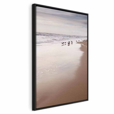 Autumn beach vertical – svart ram. Små strandfåglar står vid vattenbrynet på en bred, ljus sandstrand under en grå och disig himmel.