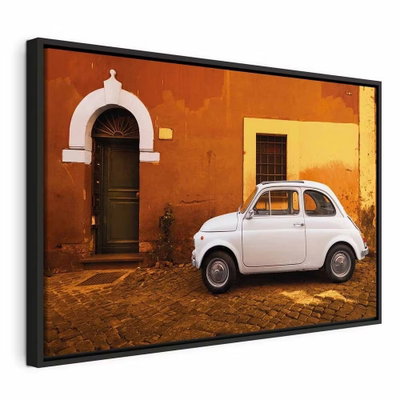Italian street wide – svart ram. En liten vit bil står på kullersten framför en orange husvägg med mörk dörr och vita detaljer.