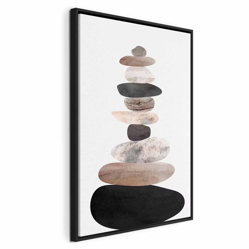 The art of balance – svart ram. Rundade stenliknande former i rosa, grått och svart ligger staplade ovanpå varandra mot en ljus botten.