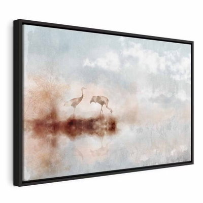 Cranes in the morning wide – svart ram. Två långbenta fåglar och deras speglingar framträder i ett disigt landskap i crème, rosa och blågrått.