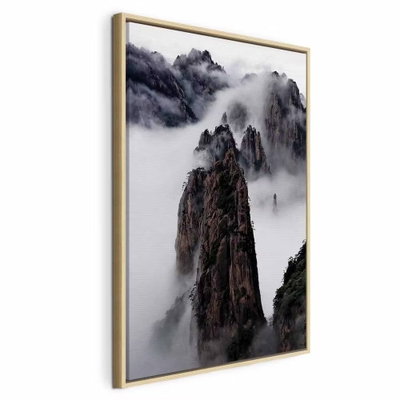 High mountains in mist – naturfärgad ram. Smala, mörka bergspelare sticker upp ur en tät vit dimma med mörka berg i bakgrunden.