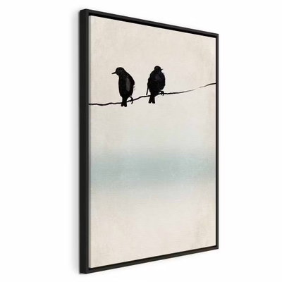 Frozen sparrows vertical – svart ram. Två mörka fågelsilhuetter sitter på en smal tråd framför en ljus bakgrund med ett mjukt turkost fält.