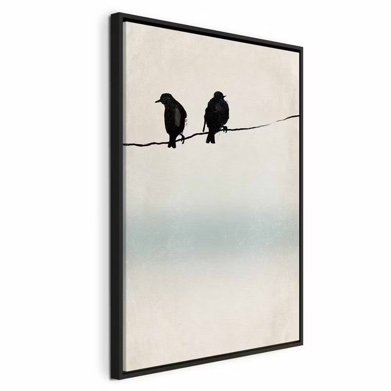 Frozen sparrows vertical – svart ram. Två mörka fågelsilhuetter sitter på en smal tråd framför en ljus bakgrund med ett mjukt turkost fält.