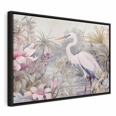 Heron wading in a pond – svart ram. En vit, långbent häger står i vatten bland rosa blommor, grågröna blad och ljusa tropiska växter.