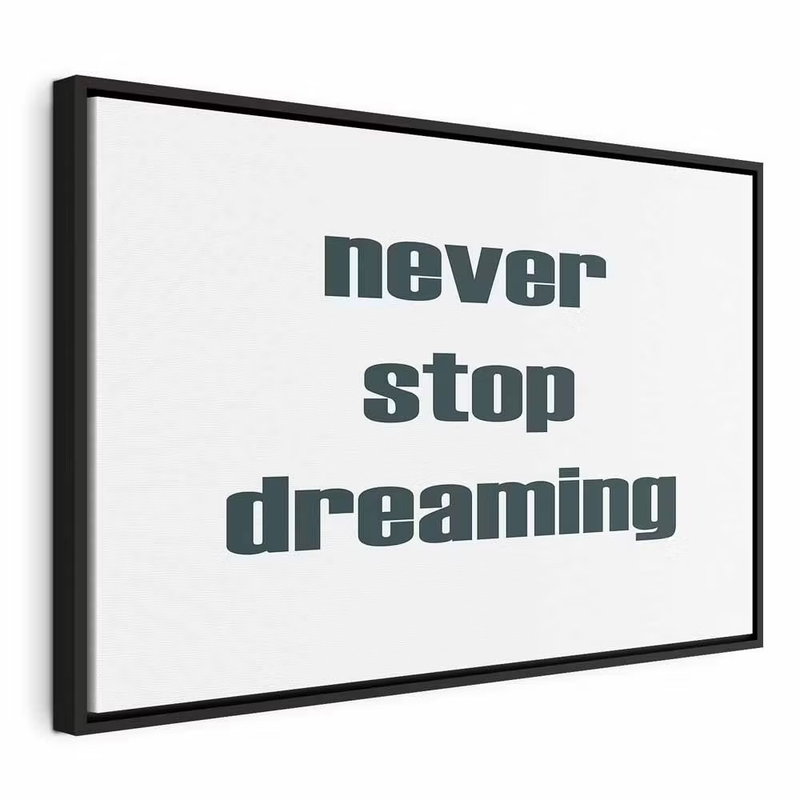 Never stop dreaming wide – svart ram. Orden never stop dreaming står i mörk, kraftig typografi på en vit bakgrund.
