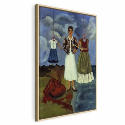 Frida kahlo memory – naturfärgad ram. En mörkhårig kvinna står mellan två upphängda dräkter under en blågrå, molnig himmel.
