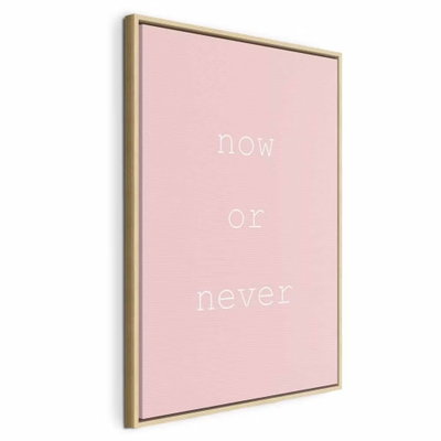 Now or never vertical – naturfärgad ram. Orden now or never återges i tunn vit typografi mot en jämnt ljusrosa bakgrund.