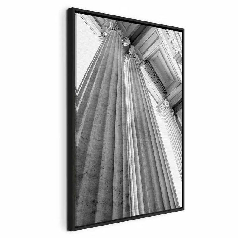 Stone columns vertical – svart ram. Höga, räfflade stenpelare ses nedifrån i svart och vitt med starka linjer mot en ljus himmel.