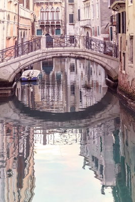 Noon in venice vertical – motivvy. En liten stenbro och täta husfasader speglas i en lugn kanal i mjuka rosa och grå toner.