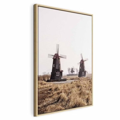 Wooden windmill vertical – naturfärgad ram. Flera väderkvarnar står i ett torrt gräslandskap under en blek himmel.