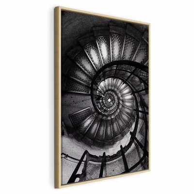 Dizziness vertical – naturfärgad ram. En mörk spiraltrappa med perforerade steg och svängda räcken bildar ett tätt, cirkelformat mönster.