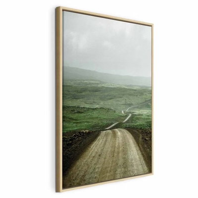 Road across the plains – naturfärgad ram. En grusväg slingrar sig genom öppna gröna slätter mot disiga kullar under en grå himmel.