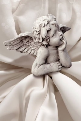 Love thoughts vertical – motivvy. En liten ljus änglafigur med vingar vilar mot mjukt veckade, crèmefärgade tyger.