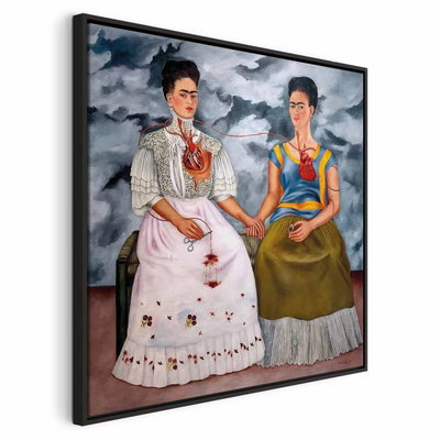 Frida kahlo the two fridas – svart ram. Två mörkhåriga kvinnor sitter hand i hand i vit respektive grön klädsel under en mörk, molnig himmel.