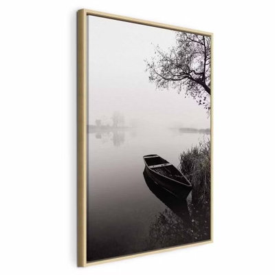 Haven under tree vertical – naturfärgad ram. En mörk träbåt ligger vid en strand under ett utsträckt träd i ett dimmigt svartvitt landskap.