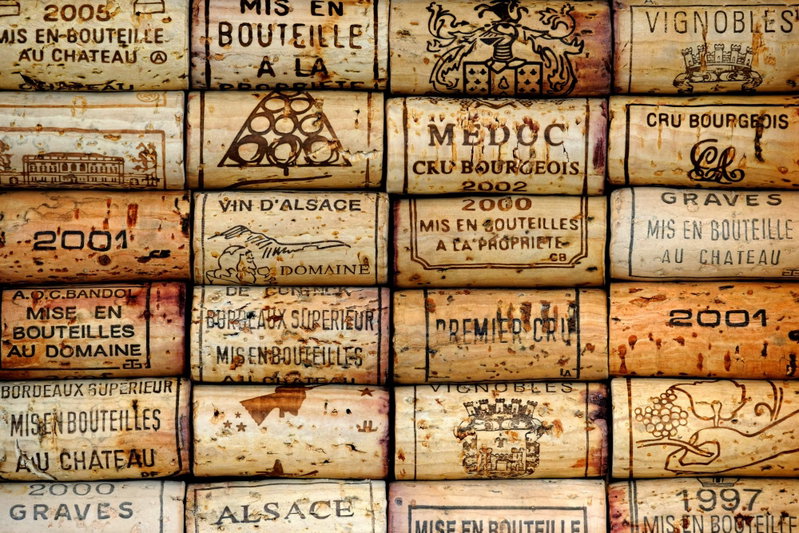 Vineyard of memories: Rader av tryckta vinkorkar med mörka texter och vingårdsnamn bildar ett varmt mönster i beige och brunt.