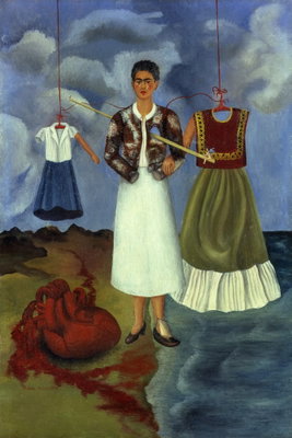 Frida kahlo memory – motivvy. En mörkhårig kvinna står mellan två upphängda dräkter under en blågrå, molnig himmel.